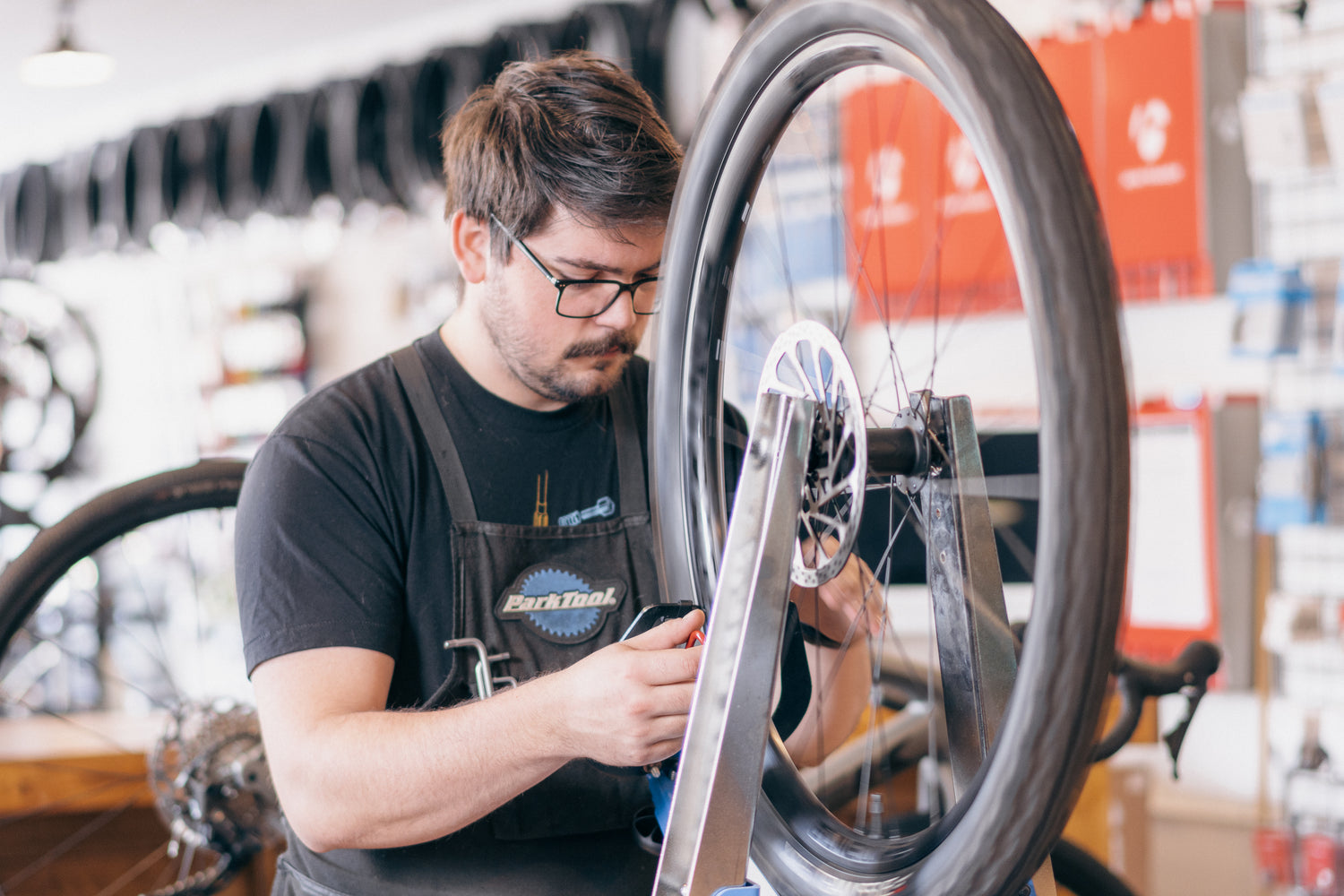 Man working on a bicycle wheel in a workshop setting